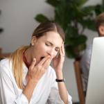 Jungte Frau gähnend vor dem PC